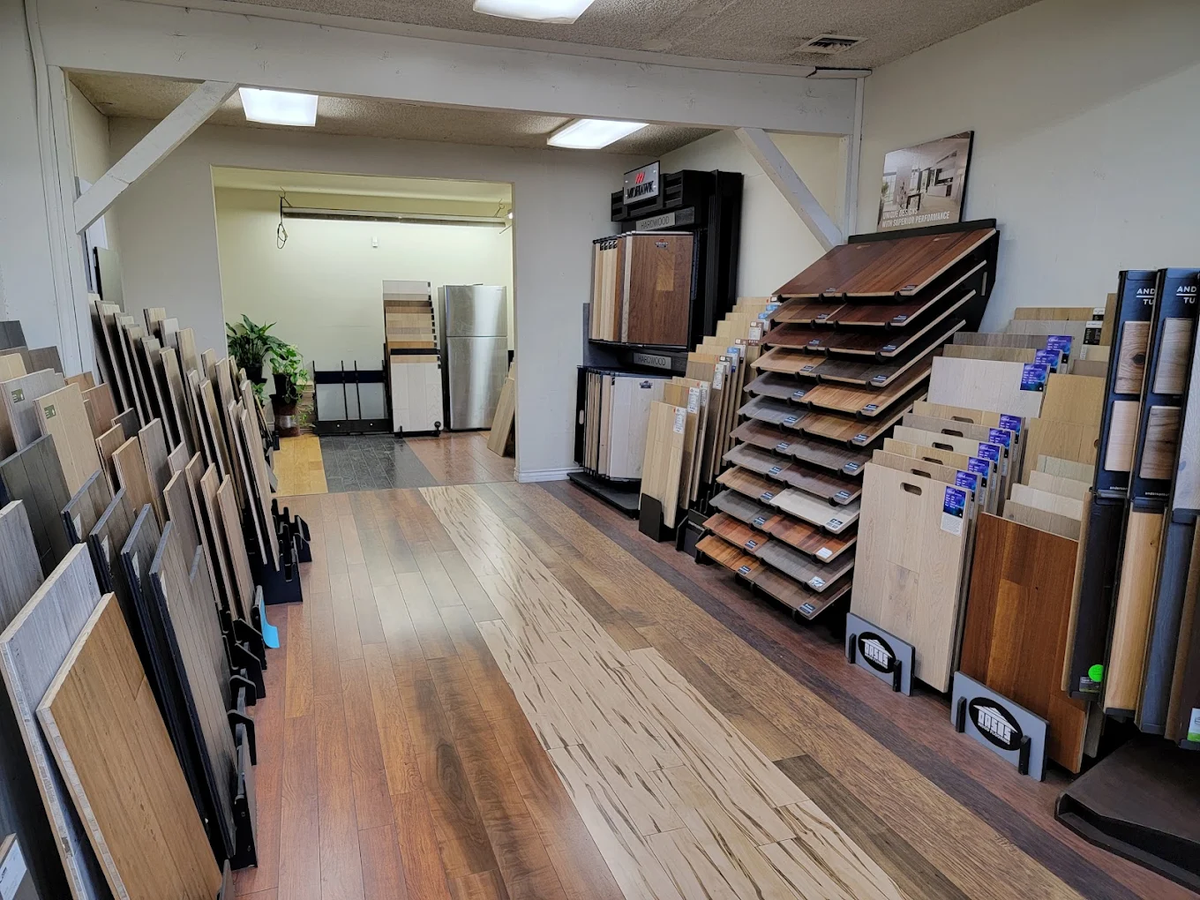 Hardwood and laminate samples lining the aisle of The Carpet Store showroom in Sylmar, CA